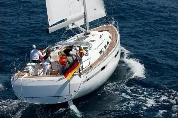 A high-angle view of a white sailboat with a German flag cutting through the deep blue sea.