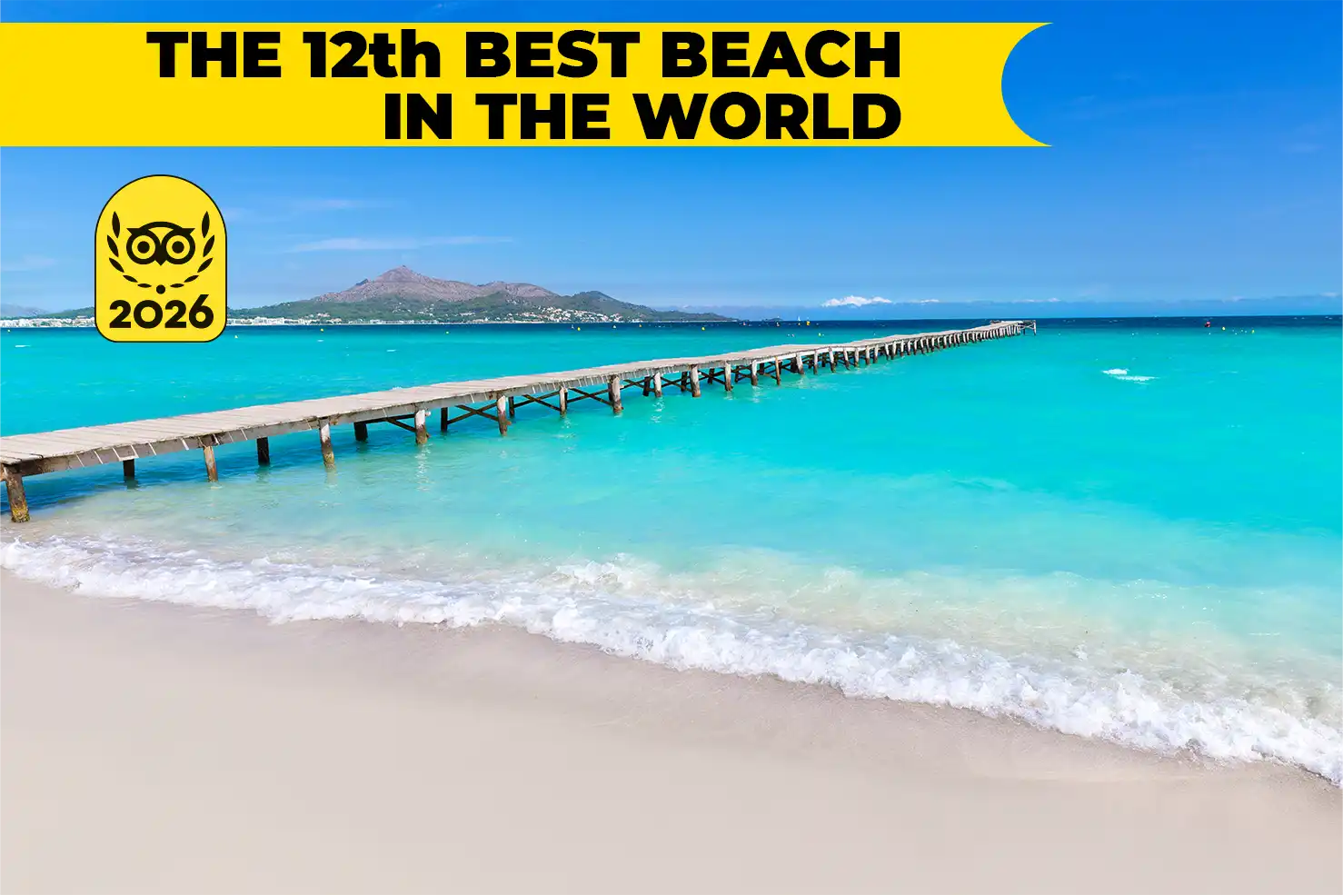 A long wooden pier stretching into the turquoise sea water at a beautiful sandy beach in Mallorca.