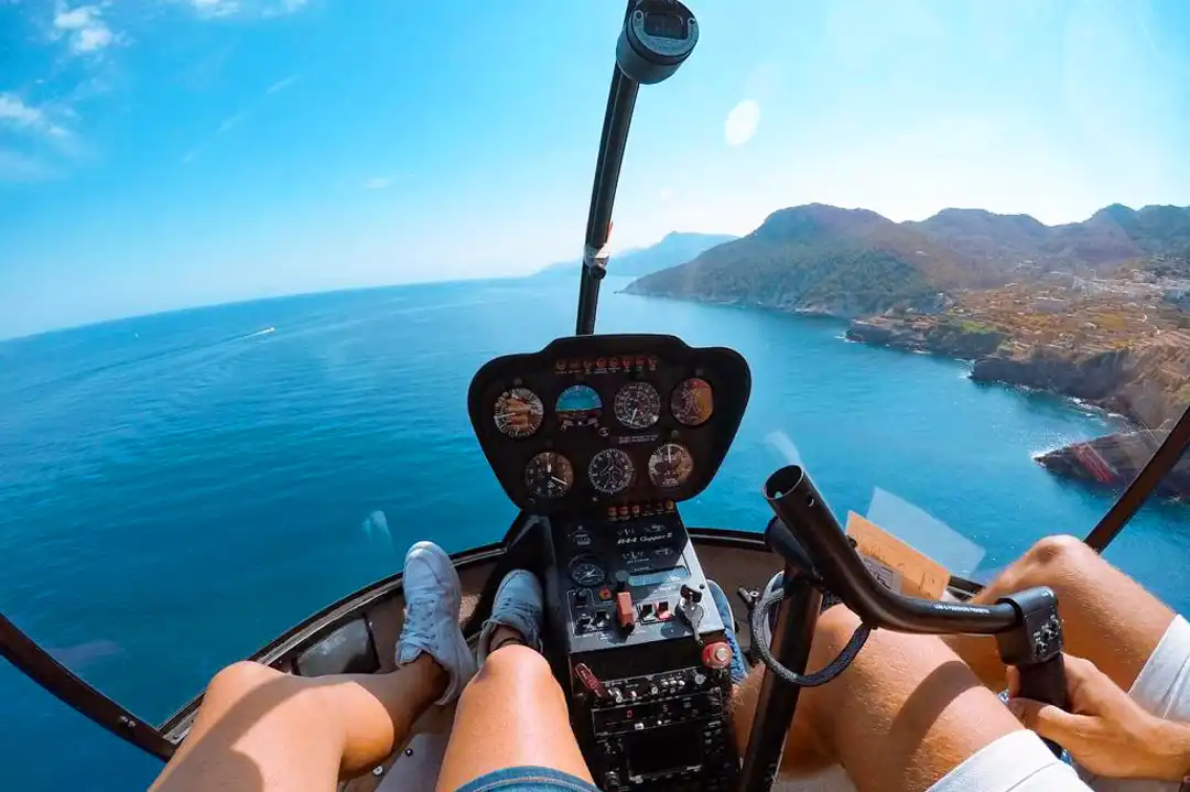 View from a helicopter cockpit flying over the blue ocean and a mountainous coastline. View from a helicopter cockpit flying over the blue ocean and a mountainous coastline.