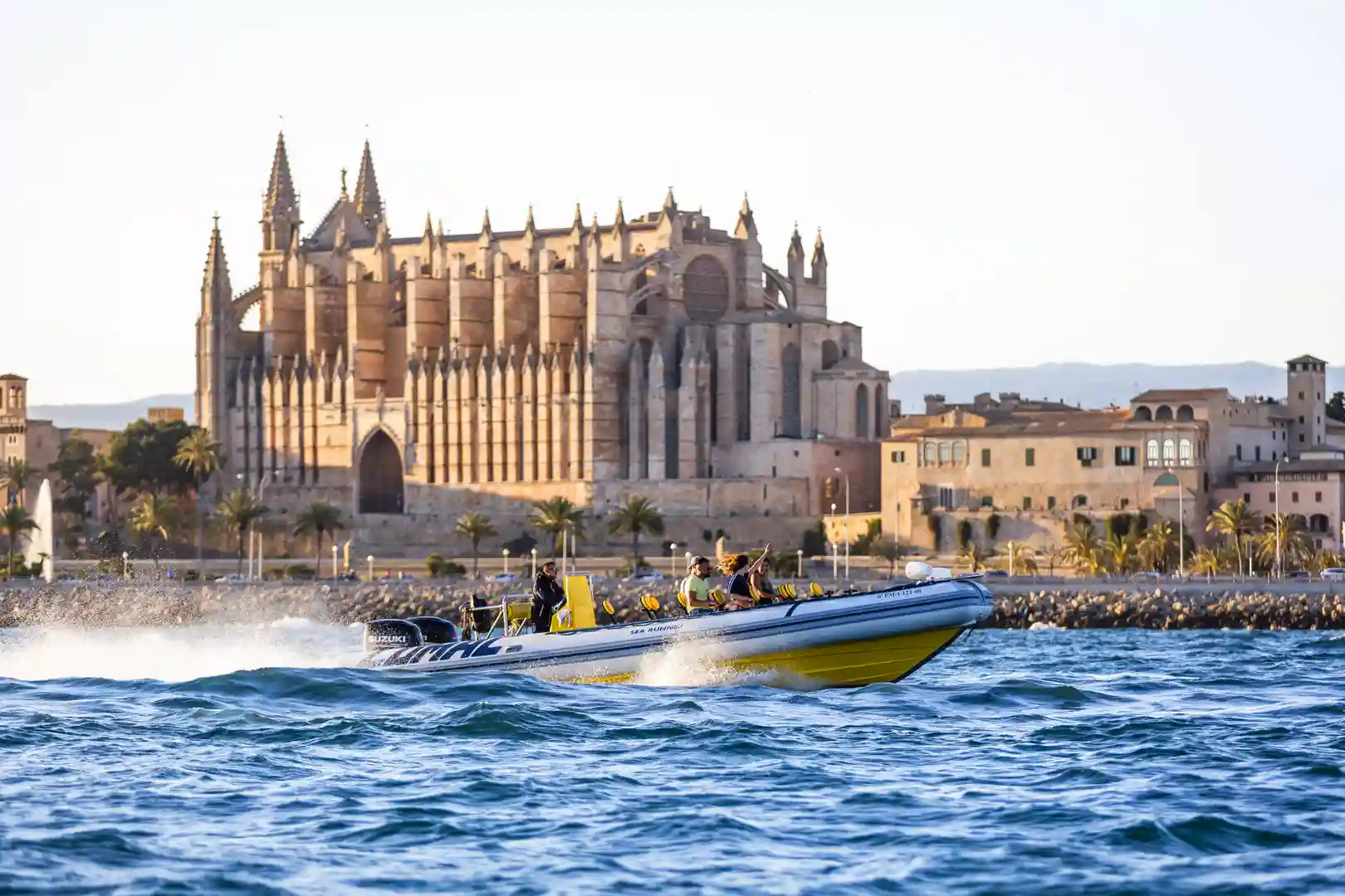 Ein schnelles gelbes und graues Boot fährt an einer großen, historischen gotischen Kathedrale vorbei. Ein schnelles gelbes und graues Boot fährt an einer großen, historischen gotischen Kathedrale vorbei.