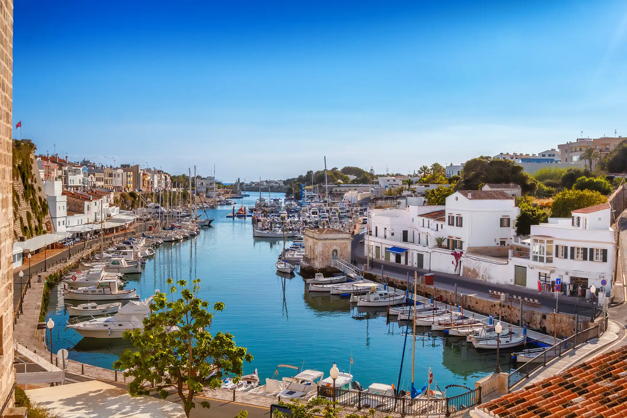 Beautiful harbor town with white houses and numerous boats moored along the calm blue sea channel.