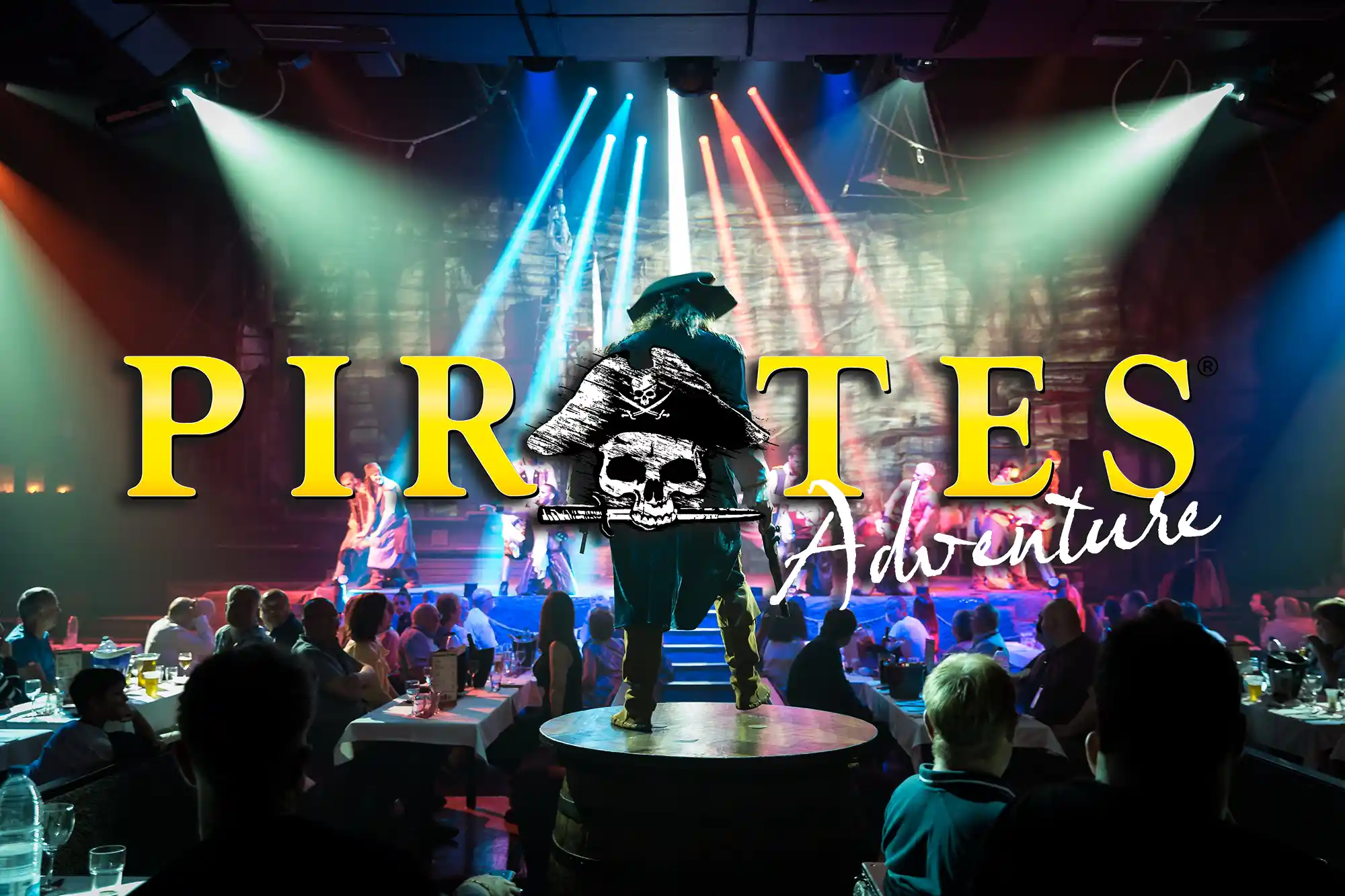 An actor performs on stage during a pirate-themed dinner show with bright lights and a large audience.