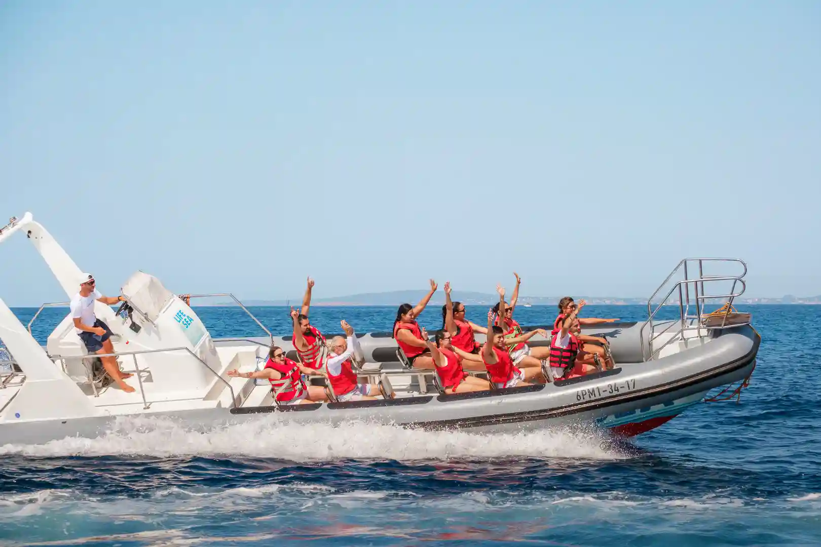 Passagiere in roten Schwimmwesten winken begeistert von einem schnellen Schlauchboot auf dem Meer. Passagiere in roten Schwimmwesten winken begeistert von einem schnellen Schlauchboot auf dem Meer.