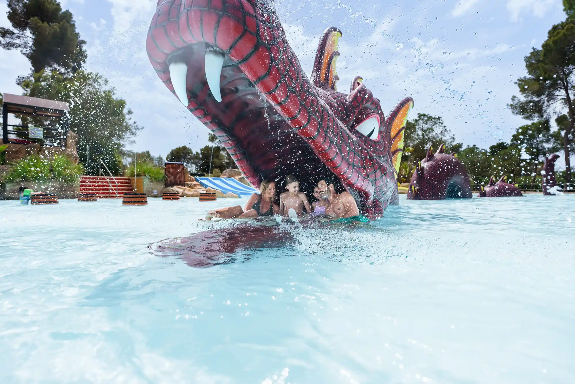 A happy family enjoying a pool with a large dragon-shaped water slide at a water park.